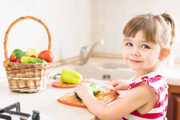 girl-in-kitchen-with-vegetables Two children enjoying a healthy lunch with fruits and vegetables in a school cafeteria.